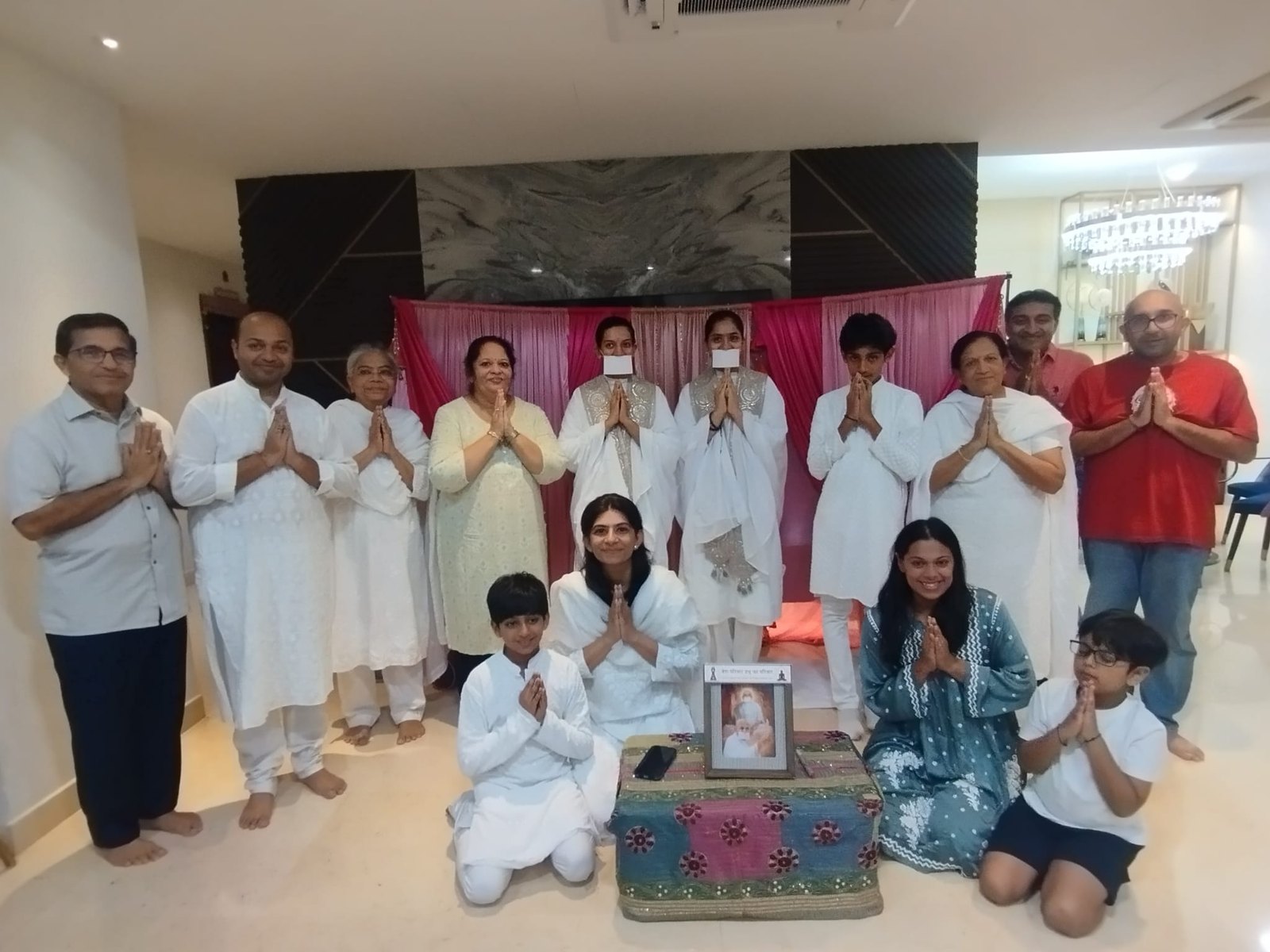 Families with folded hands around the mumukshus at a home visit